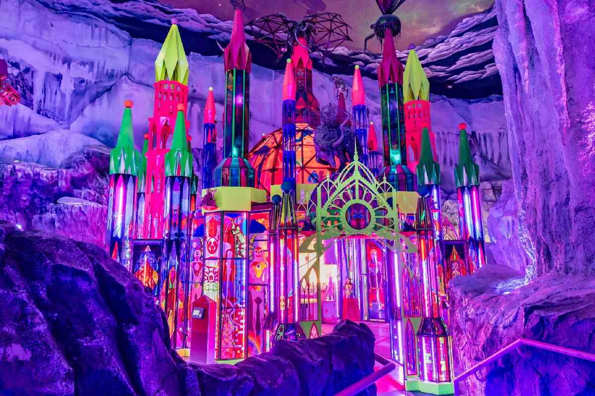 A multicolored cathedral structure with stained glass windows and nestled within an ice cavern.